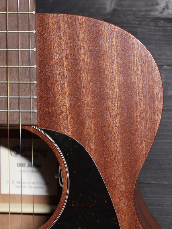 Close-up of the solid Sapele top on the Martin 000-Jr guitar upper bout with fretboard 